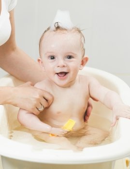 Portrait of cheerful smiling baby boy having bath with foam