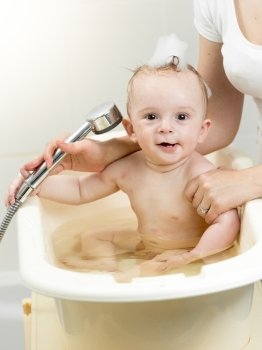 Funny portrait of cheerful baby boy playing in foam at bathroom
