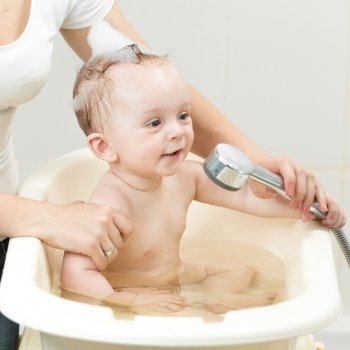 Closeup photo of mother bathing her cute baby in bathroom