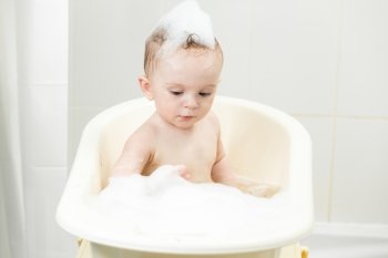 Portrait of adorable baby boy playing with foam in bath