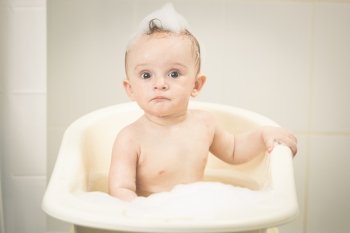 Toned portrait of adorable baby boy having bath time
