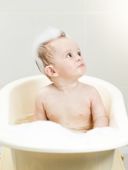 Portrait of cute baby boy having bath with foam