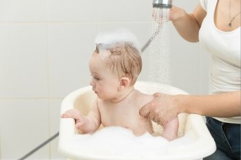 Portrait of cute baby boy sitting in bath full of foam