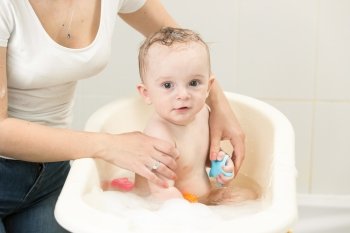 Portrait of cute baby boy having bath and playing with toys