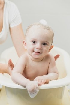 Portrait of cute smiling baby sitting in bath and looking at camera