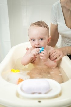 Portrait of cute baby boy playing with toys while having a bath