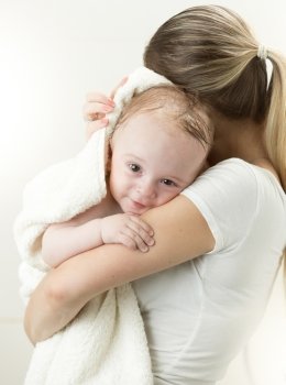 Portrait of cute baby boy hugging mother after having bath