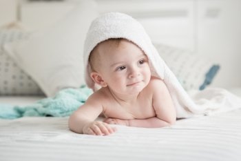 Portrait of happy 9 months old baby looking under towel after having bath