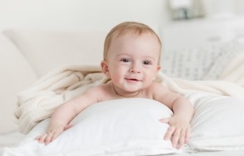 Portrait of cheerful smiling baby boy lying on big bed