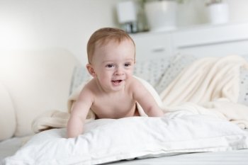 9 month old baby boy crawling over pillows on bed