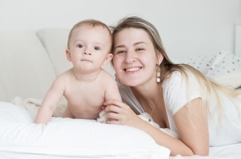 Closeup portrait of happy smiling baby boy and mother lying on pillow and looking at camera