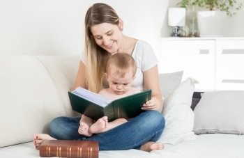 Beautiful smiling mother reading story to her 9 months old baby boy