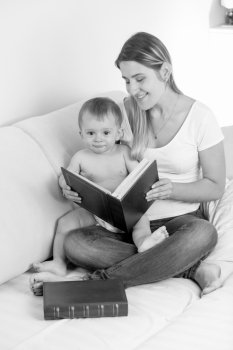 Black and white image of young smiling mother looking at photos in album