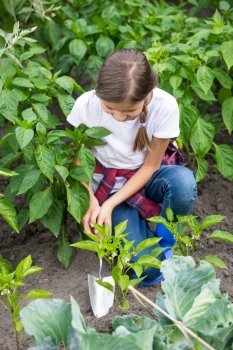 Beautiful young girl digging earthing soil at vegetable garden bed