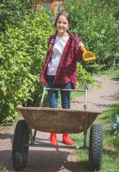 Beautiful smiling teen girl in wellies working in garden