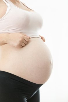 Side view of young pregnant woman showing big belly over white background