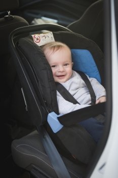 Portrait of cute smiling baby boy sitting in car child seat