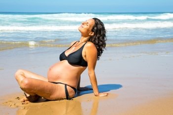 Happy pregnant woman on the beach at the atlantic ocean