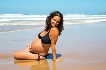Happy pregnant woman on the beach at the atlantic ocean