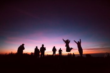Group Of People relaxing on field with sunrise
