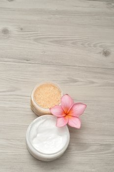 Body lotion and bath salt displayed with a frangipani flower