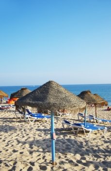 parasols and sun loungers on the beach on Faro island, Algarve. Portugal