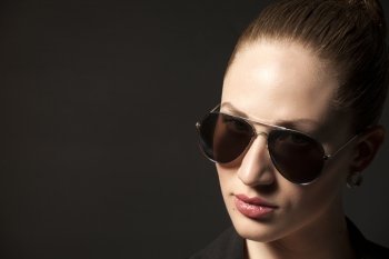 Portrait of Beautiful young woman in sunglasses on black background