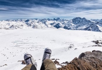 Feet selfie of snowboarder resting and enjoying the view of mountains. Elbrus, the northern Caucasus mountains, Russia