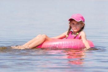 Sad girl in a cap floating in the river sat on the swimming circle