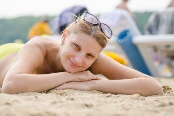 Young girl lying on sandy beach and smiling looks into the frame
