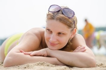 Young girl lying on sandy beach and looking to the side