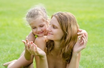 Mom and daughter having fun embrace the summer picnic on a green lawn