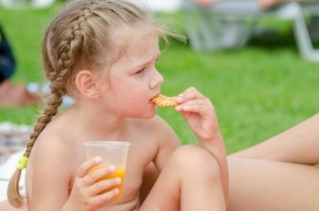 Girl eating cookies and drinking juice from a plastic disposable cup