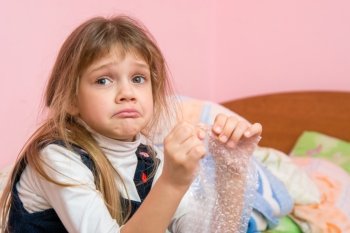 Upset girl pouting cheeks eats bubbles packaging film and looked for someone