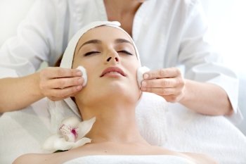 Spa salon: Beautiful Young Woman having Facial Treatment in Spa salon with White Orchid.