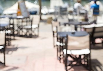 Background of blurred cafe on street of city. Tables and chairs outside in natural bokeh