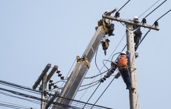 Selective focus of electricians are fixing power transmission line on a electricity pole