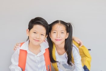 Lovely Asian couple school kids, 7 and 10 years old, over gray background