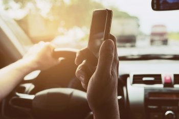 Close up of a man driving car dangerously while using mobile phone