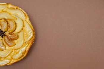 Whole tarte Tatin apple and pear tart pie isolated on light brown background with copy space