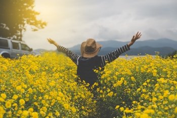 young woman raise her hand up in yellow Chrysanthemum flower field, feeling happy and free