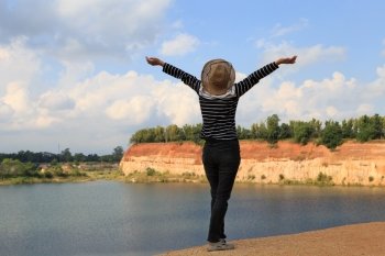 woman raise her hands up feeling happy and free at orange hill and green pond