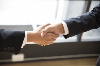 two businessman shaking hands beside window - business teamwork, cooperation concept