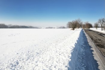 Rural winter scene with snowy field and road.