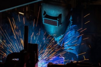 worker welding automotive part in car factory