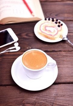 cup of coffee and a mobile phone on a brown table, close up