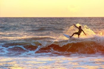 Surfer surf in the ocean at sunset. Bali island
