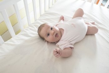 Baby in a baby bed. White clothes. Window light