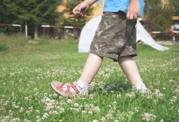 Child walking on the meadow with flowers