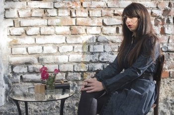 Woman sitting on a chair in coffee shop. Vintage brick wall background